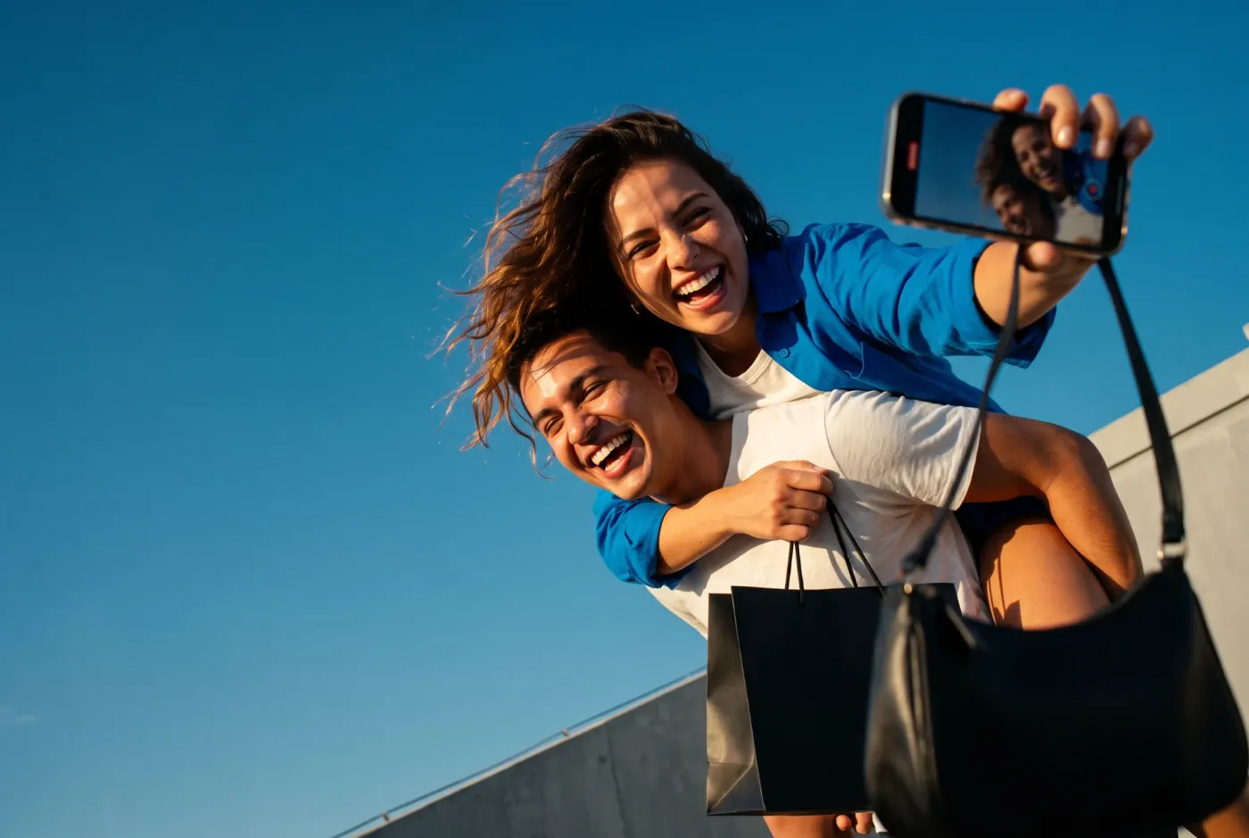 Casal sorrindo numa selfie com sacola de compras ao ar livre