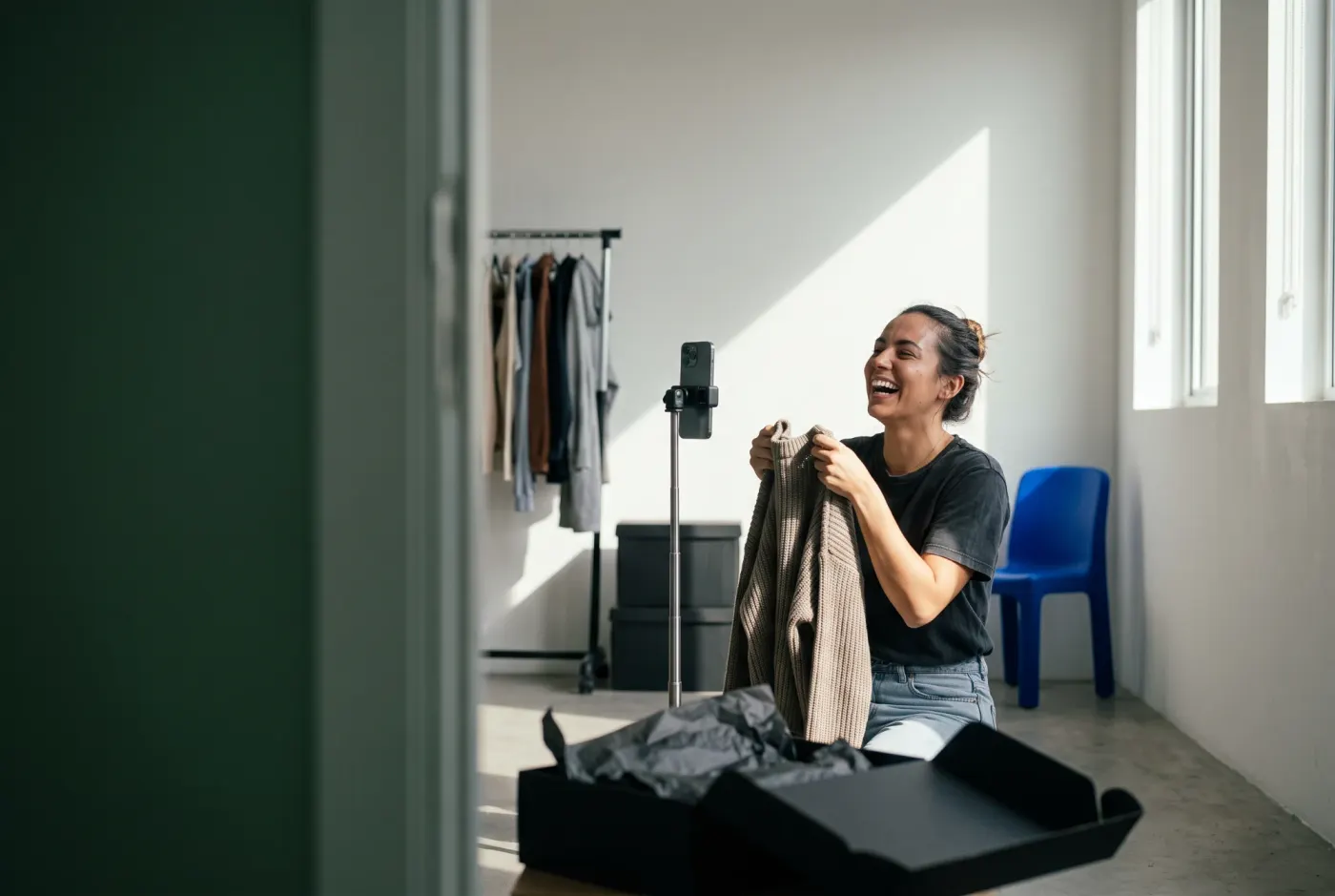 Creator gravando vídeo com o celular no tripé enquanto mostra uma peça recém-chegada